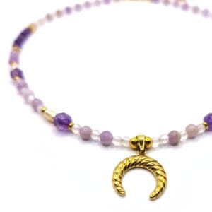 Zbliżenie na wisiorek w kształcie rogu obfitości oraz kamienie Perła, Ametyst i Jadeit Lawendowy w naszyjniku.