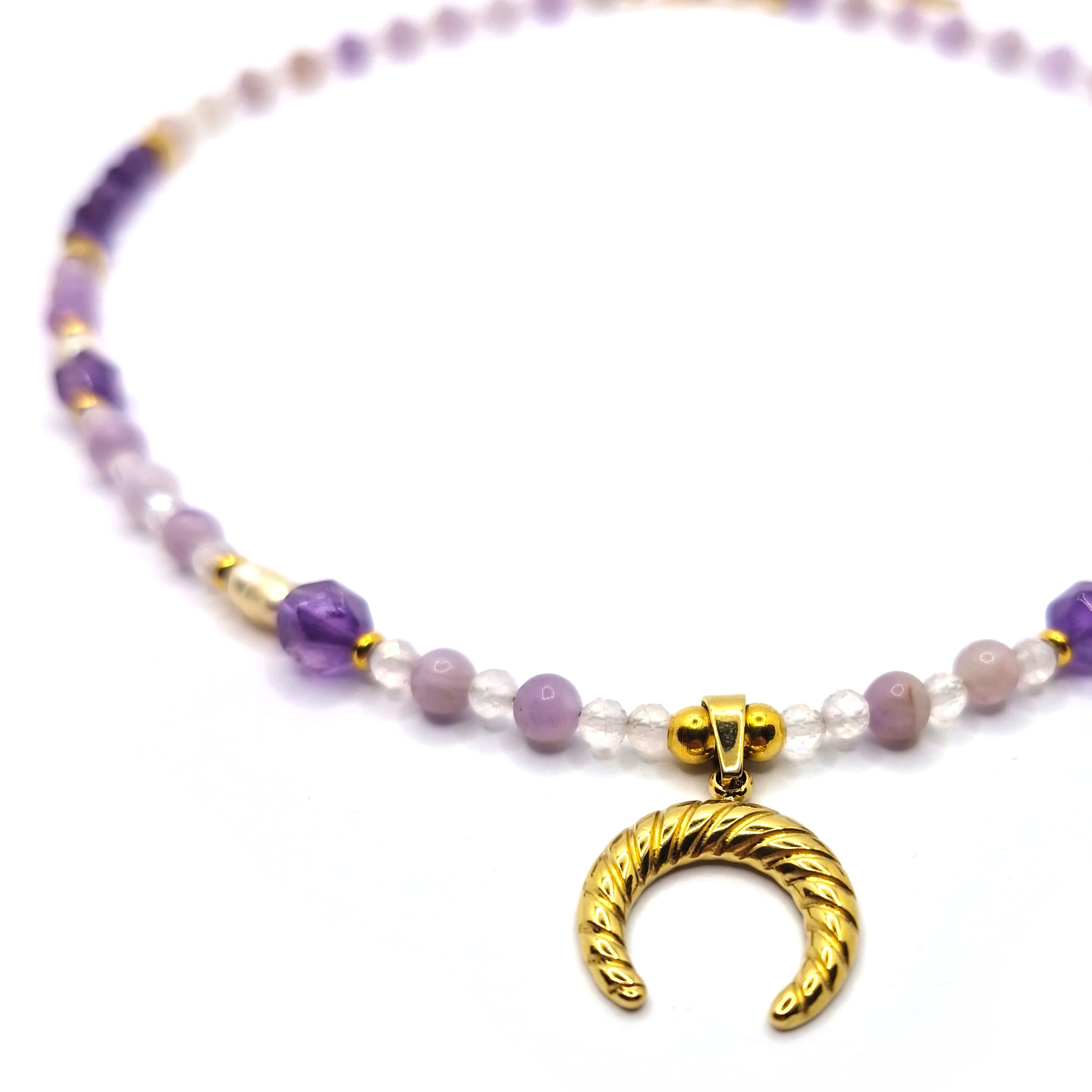 Zbliżenie na wisiorek w kształcie rogu obfitości oraz kamienie Perła, Ametyst i Jadeit Lawendowy w naszyjniku.