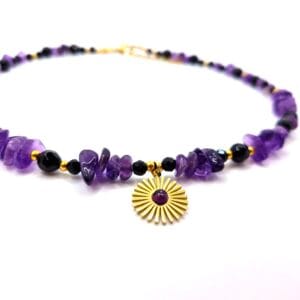 Naszyjnik wykonany z naturalnych bryłek fioletowego ametystu i czarnego onyksu ze zawieszką w kolorze złotym w kształcie słońca.