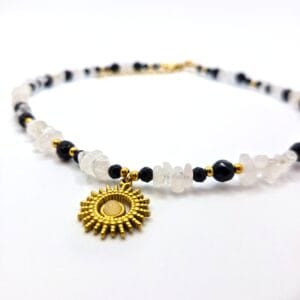 Naszyjnik z naturalnego białego kryształu górskiego i czarnego onyksu z centralną zawieszką koloru złotego w kształcie słońca.