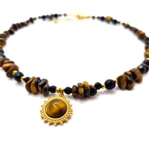 Naszyjnik w kolorze złotym z zawieszką słońca wykonany z naturalnych bryłek kamienia tygrysie oko oraz czarnego onyksu.